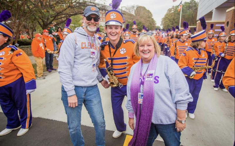 Dawson Baker, center, marches alongside his father Kevin Baker, left, and mother Lisa Baker, right, during Senior Day festivities at Clemson University before kickoff versus the University of Miami.