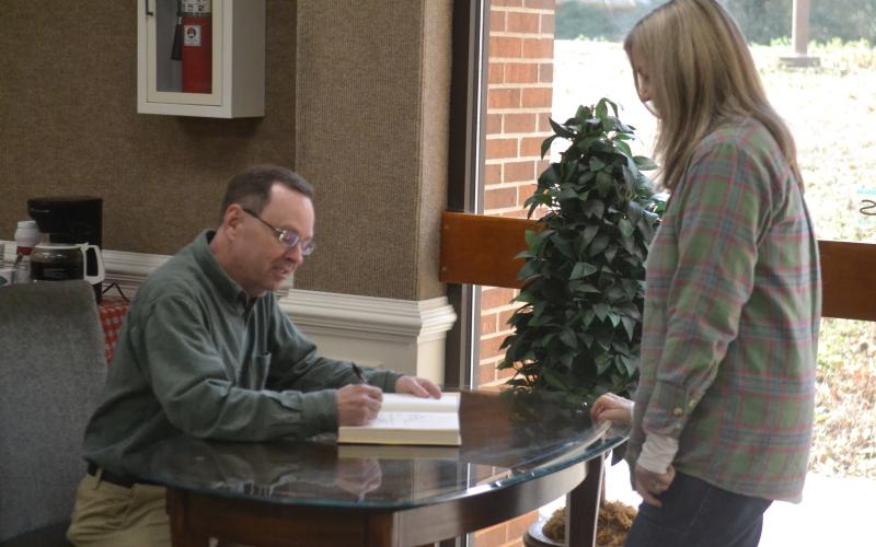 New York Times bestselling author John Cribb (left) signs a copy of his latest book, “The Rail Splitter” for Gwen Walters (right), of Hartwell, during a book signing and talk at the Hart County Library Jan. 26.