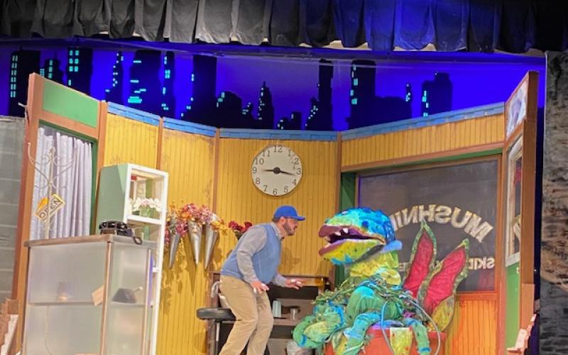 Actor Ethan Smith as Seymour speaks to Audrey II controlled by puppeteer Elna Brynestad.