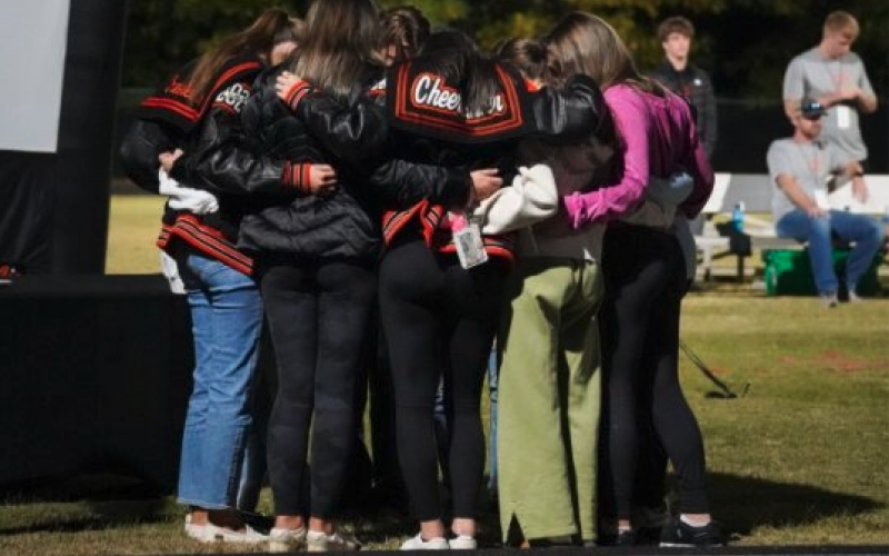 Pictured in the middle is the competition cheer team praying with head coach Mollie Payne.