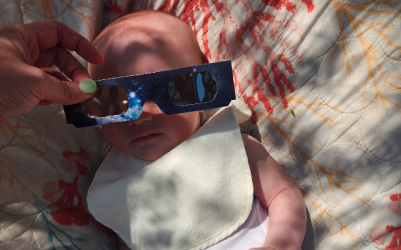 Hartwell native Lacey Bailey holds up the glasses for her three-month-old great nephew Wylder Ouzts as he watches his first solar eclipse.