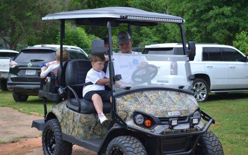 Jackson Moon and his father Zachary riding in their brand new golf cart from the Make-A-Wish Foundation.