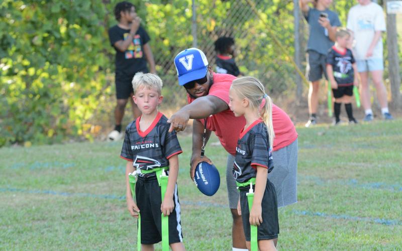 Pictured from left is Mercer Leard, coach Darryl Lewis, and Anna Starrr as Lewis is showing them how to run the next play.