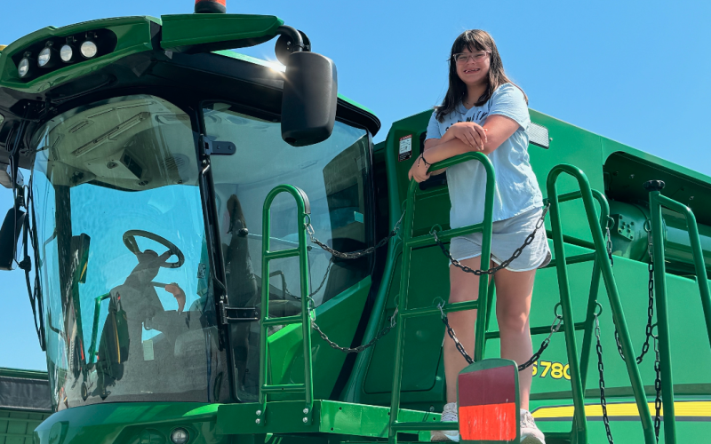 Vivian Fargason poses for a picture with an enormous piece of farm equipment during the 2024 Northeast Georgia Ag Expo.