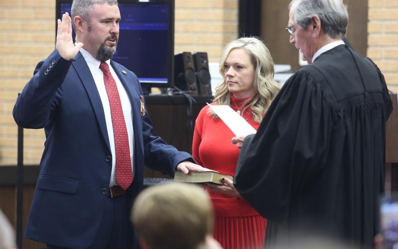 Chris Carroll (left) repeats the oath of office for Hart County Sheriff from Northern Judicial Circuit Superior Court Judge Chris Phelps (right) as his wife, Nichole, holds the Bible inside the Hart County Courthouse.