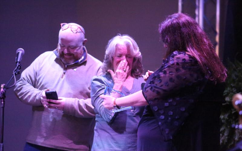Debbie Kulcsar reacts to being named the Community Champion by Hart County Chamber of Commerce Executive Director Amanda Brown as Downtown Development Authority Director Jason Ford smiles in the background during the chamber’s annual awards banquet Feb. 21 at The Station of Hartwell.