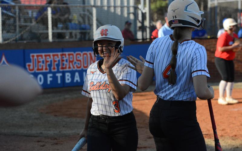 Sophomore Carly Dutton (left) celebrates with junior Madi Bennett (right) after coming home to score a run. (Photo/Benjamin London)