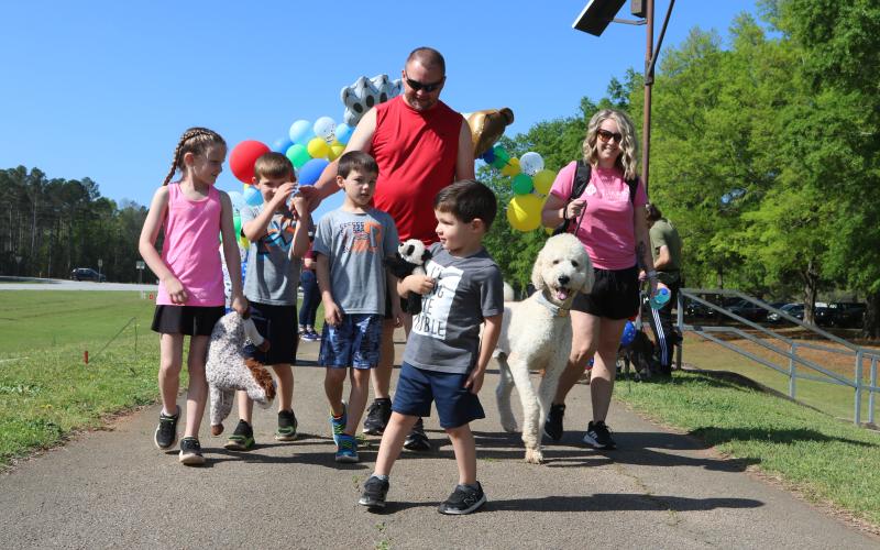(L-R) Layla Evans, 8, Noah Evans, 7, James Evans, 9, father Matt Evans, Chief Evans, 4, and mother Amy Evans, walk Teddy, a two-year-old poodle, through the balloon arch at the Dam Dog Walk event. (Photo/Adriana Cascio)