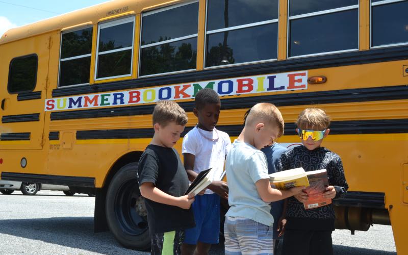 Children at the Hart Youth Development Resource Association (HYDRA) show off their books to each other outside the Hart Partners Bookmobile on Tuesday. The Bookmobile provides free snack bags and books for all children age groups, from toddlers to teenagers, throughout Hart County. (Photo/Adriana Cascio)