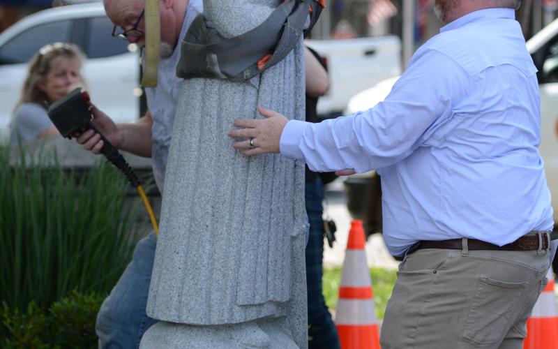Hartwell Economic and Community Development Director Jason Ford (right) helps hold the statue in place as Mart Clamp helps adhere the statue to its pedestal (left). (Photo/Benjamin London)