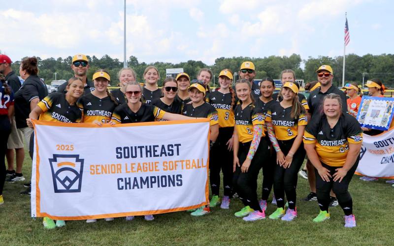 Hart County Senior League Softball team poses with their Southeast Champions banner before a game in the Senior League Softball World Series in Lower Sussex, Delaware. The team consists of Milo Allen, Marlee Bowers, Maggie Bridges, Ky Dubose, Kinsley Duncan, Peyton Jordan, Emory McCollum, Peyton McCollum, Emma Mitchell, Kam Price, Erika Royston, Bella Segars, Chesnee Strickland, EmmaKate White and MaryBeth White. The team is coached by Kyle McCollum, Mason Bowers, Tony Strickland and Head Coach Paul Mitchel