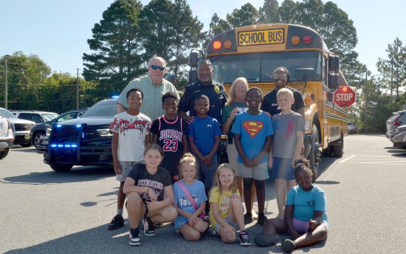 Hartwell Police Department Lt. Darin Rucker shows off a Hart County Charter System bus’s safety features to children at the Bell Family YMCA, located at 281 Opal Ext., on Tuesday. All buses are equipped with flashing lights, a stop sign and a crossing arm to ensure the safety of students entering and exiting the vehicle. (Photo/Adriana Cascio)
