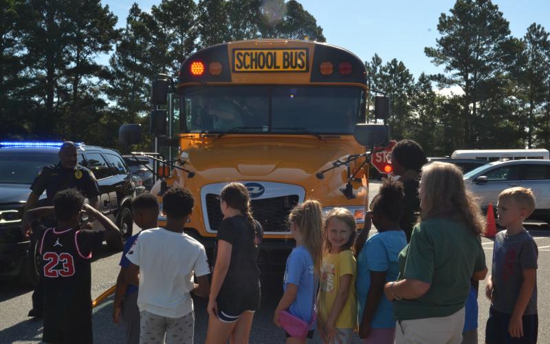 Hartwell Police Department Lt. Darin Rucker shows off a Hart County Charter System bus’s safety features to children at the Bell Family YMCA, located at 281 Opal Ext., on Tuesday. All buses are equipped with flashing lights, a stop sign and a crossing arm to ensure the safety of students entering and exiting the vehicle. (Photo/Adriana Cascio)