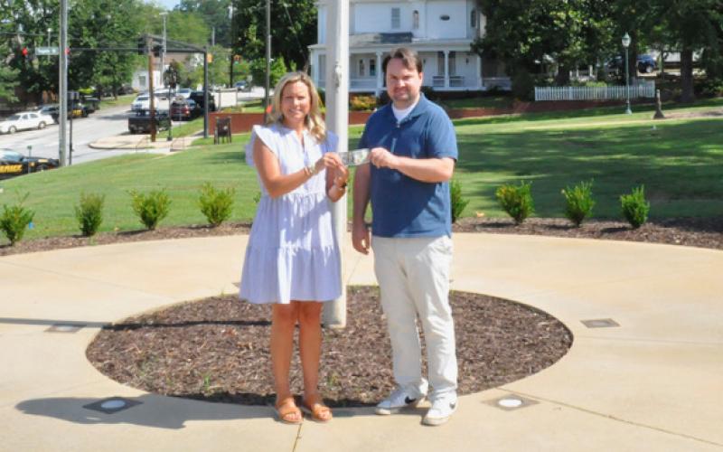 The Toccoa Record Publisher Michael O’Hearn, right, presents Kim Caudell of Toccoa with the $100 she won for her photo in the 2025 summer Lake Living cover contest. (Photo by J. Todd Truelove, The Toccoa Record)