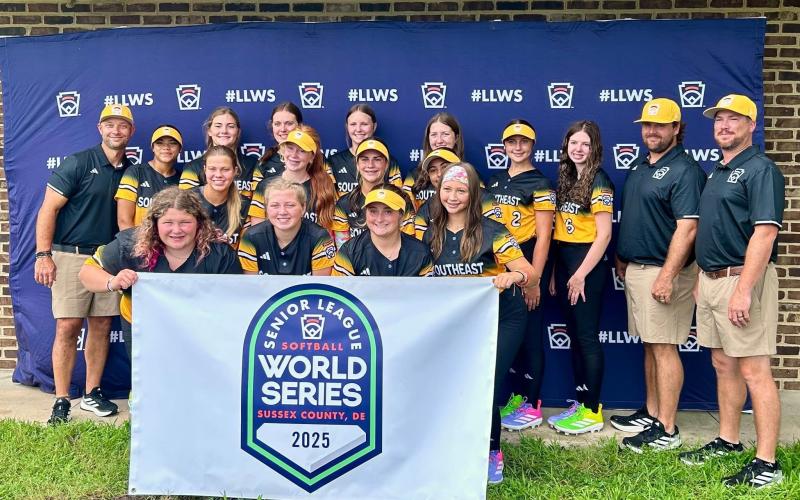 Hart County Senior League Softball team poses with a Senior League World Series banner before a game in the Senior League Softball World Series in Lower Sussex, Delaware. (Photo courtesy of Hart County Little League)