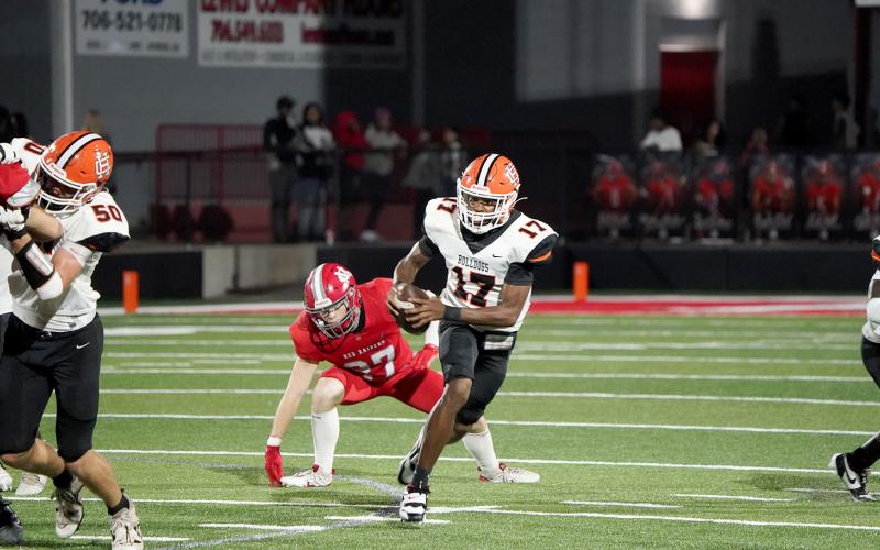 Junior quarterback Kurston Curry evades the pressure from the Red Raiders defense in the 28-14 loss to Madison County Aug. 22. (Photo by Ric Williams)