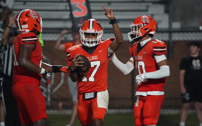 (From left) Junior running back Faustino Rangel, junior quarterback Kurston Curry and junior wide receiver PJ Johnson moments after taking the final kneel to complete the 31-28 upset of the top ranked Wolverines of Prince Avenue Christian Sept. 26. (Photo by Ric Williams)