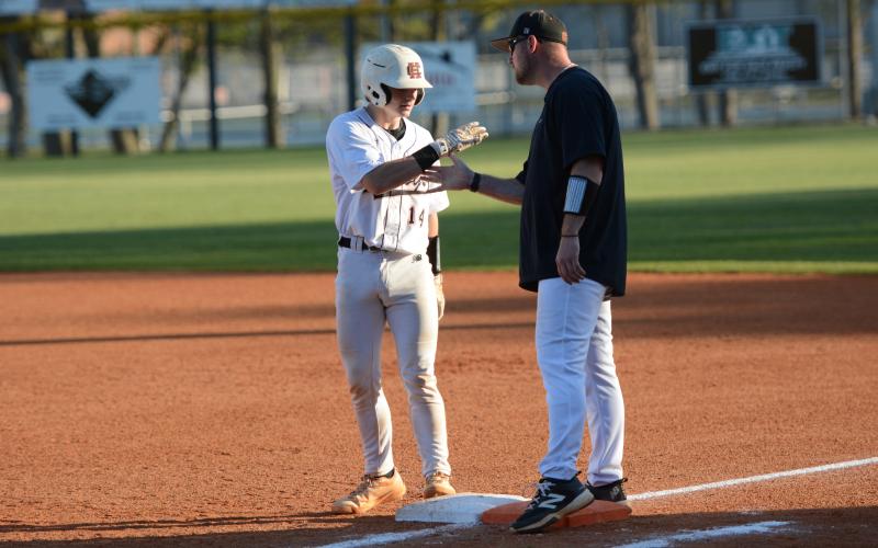 Sophomore catcher Slate Osborne celebrates with first base coach Chris Wilson after pushing across two runs in the 15-2 loss to Franklin County March 23. Photo by Benjamin London.