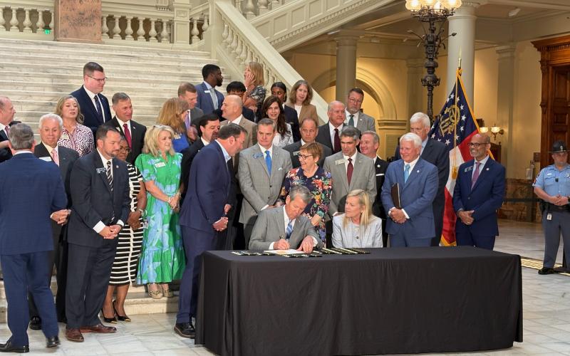 Gov. Brian Kemp selects a pen to sign tax legislation at the Georgia Capitol in Atlanta on Monday, with wife Marty by his side. House Speaker Jon Burns, R-Newington, watches to her left. Photo by Ty Tagami.