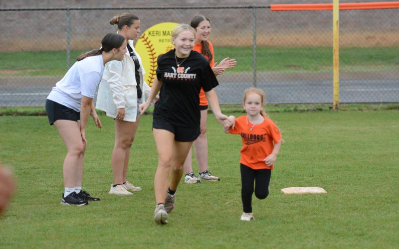 Rising senior infielder Carly Dutton (left) rounds the bases with a camper during the annual Little Bulldog Softball Camp June 8-10. Photo by Benjamin London.