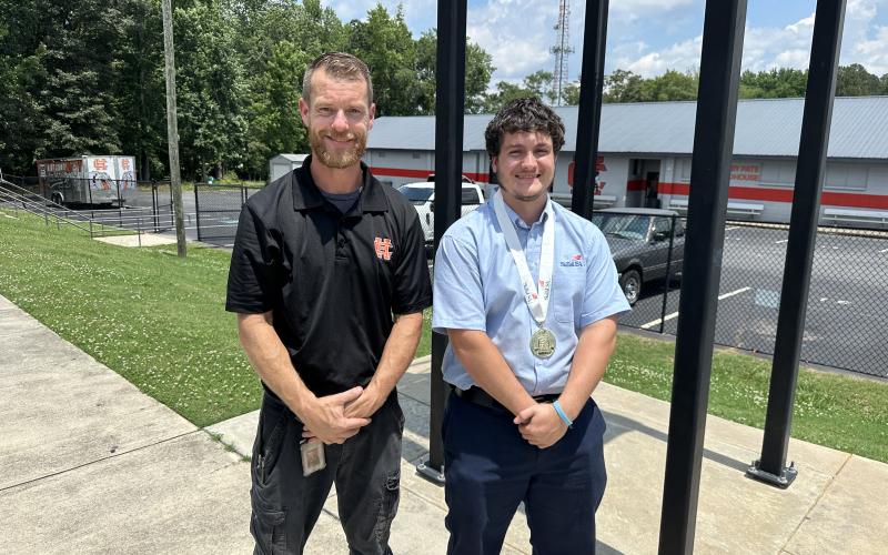 Jimmy Reynolds (right) poses for a photo with Marine Engine Technology instructor Tyler Floyd (left) after ringing the Victory Bell at Hart County High School following his National Championship win. Photo by Grayson Williams.