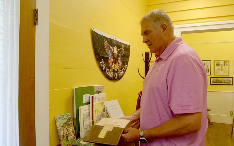 The Hart County Museum is located at 31 E. Howell St., in the Teasley-Holland House. Inside, museum-goers will find old artifacts donated from the public, such as the book Hart County Historical Society board chair Allen Stewart holds. They can also find AI-generated reworks of real, old photographs from Hart County's pre-consolidated schools and churches that allow them to be colorized and showcase similar-appearing people. Photo by Madison Linton.