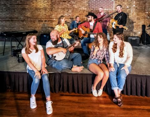Sunshot by Bill Powell Pictured are Nash McCan and the McCan Family Band. Front row: Ella Long, Seth Howard, Victoria Evans amd Olivia Berry. Second row:  Andrea Bradford and Nash McCan (Josh Bryan). Back Row:  Kevin Long, Casey Middlebrooks and Jody DiMarco. Not Pictured: David Phillips and Jamee Floyd.
