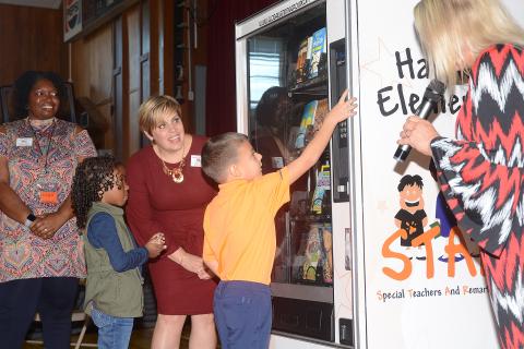 Sunshot by Michael Hall — Kindergartener Duke Swafford reaches up to press the buttons of Inchy’s Bookworm Vending Machine on Oct. 25 at Hartwell Elementary as vice principal Ashley McNeil, from left, second-grader Jordynn Ashmore, media specialist Erin Gaines and principal Lydia Bennett, right, look on. 