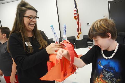 Sunshot by Michael Hall — North Hart Elementary School Teacher of the Year Emilee Patrick helps Ryan Belanger put a jetpack he invented on his back during the recent Invention Convention at the Agriscience Center. 