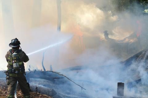 Sunshot by Grayson Williams — Hart County Firefighter Teddy Gibson douses the flames of a fire that burned a vacant mobile home on Whippoorwill Trail on Sept. 25.