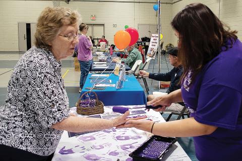 Sunshot by Karen Sokol — Carolyn Mullenix, left, has her hand painted purple by Isabel Bocanegra, right, to take the Purple Pledge with the Northeast Georgia Council on Domestic Violence for Domestic Awareness Month at the Hartwell Helps EXPO on Oct. 5.