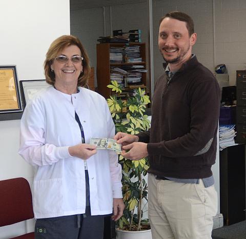 Elaine Jones, left, receives her $100 reward for winning the Lake Living winter cover contest from The Hartwell Sun publisher Michael Hall.
