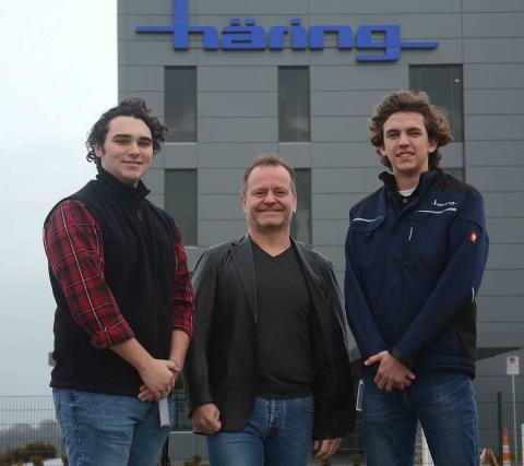 Sunshot by Michael Hall — Hart County High School students Garrett Stone, left, and Lincoln Zemaitis, right, pose for a photo with Dr. Jürgen Häring outside the Häring Precision USA factory currently under construction in the Gateway III industrial park in Hart County. 