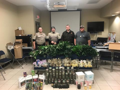 Sunshot from file — Hart County Sheriff’s deputies Luke Bennett, Michael Davis, Jared Tollinson and Capt. Kevin White pose for a photo with an array of marijuana plants and marijuana-related products allegedly being grown and manufactured at a house on Lanier Street in Hartwell.