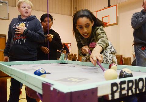 Sunshot by Michael Hall - Fifth-grader Deanna Howell lines up a shot on the Periodic Pool Table while Landry Carter and José Mendez look on on Jan. 31 at South Hart Elementary. 