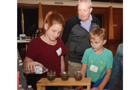 Mackenzie Marlow, left, pours water into soil to see how well it filters through as Ron Wright, of the Golf Course Superintendents Association of America, center, and Chase Moriarty look on at Cateechee in November during the first, First Green field trip at the golf club and conference center.