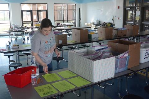 Sunshot by Michael Hall — Andi Swann, a paraprofessional at North Hart Elementary, looks for supplies to give to a family who drove through the parking lot at the school on Friday to pick up learning materials for home learning.