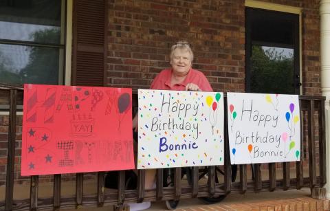 Sunshot by Kerri Pruitt — Bonnie Granville poses for a photo with signs made for her birthday parade by friends, former colleagues and students.