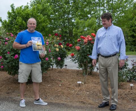 Photo by Kimberly Brown — Spring Lake Living cover contest winner Douglas Whiddon, left, of Cleveland, receives his $100 prize from Alan NeSmith, publisher of CNI Newspapers’ Lake Living. Whiddon is holding his photo of a sailboat in the sunset on Lake Lanier, which will be featured on the spring edition of Lake Living, on newsstands now.