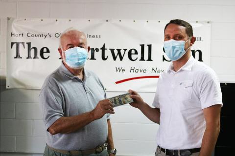Sunshot by Grayson Williams — Photographer Bill Powell, left, accepts the $100 prize for winning the Summer Lake Living cover photo contest from The Hartwell Sun publisher Michael Hall. 
