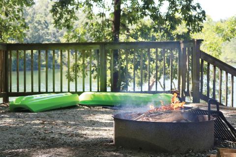 Sunshot by Grayson Williams — A fire burns in a fire pit as kayaks wait to hit the water at a Hartwell Lakeside campsite recently.
