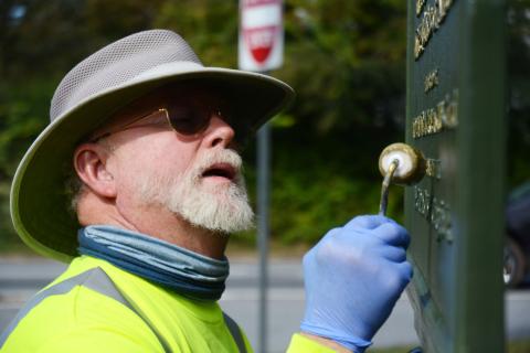 Tom Stelling carefully dabs gold paint on the lettering of the Blue Star Memorial at the corner of Athens and Howell streets in Hartwell on Oct. 25. 