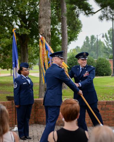 Col. Seth Graham, 14th Flying Training Wing commander, middle, hands Col. Jeffery Welborn, 14th Mission Support Group commander, right, the 14th MSG guidon at the 14th MSG change of command ceremony on July 13, 2020, at Columbus Air Force Base, Miss.