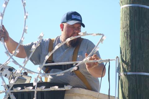 Justin Saylors fixes a lighted snowflake to a utility pole on Depot Street Tuesday afternoon. 