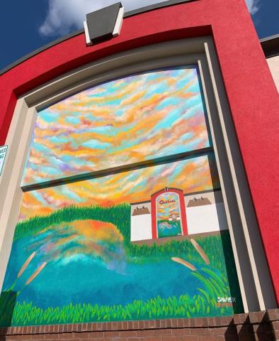 The new Guthrie's building sports a mural of itself during a sunset.
