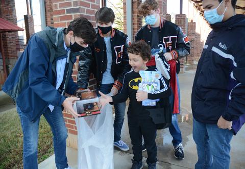 Hart County High School seniors Adam Walters, from left, Ben Tellano, Sean Leard and Tahj Courage give gifts they bought at Walmart to Damien Jones, a second-grader at Hartwell Elementary. 