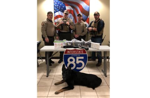 Capt. Josh Fowler, deputy Matt Sparrow, deputy Brian Anderson, Inv. Michael Davis and K-9 unit “Chuck” pose for a photo with more than 11 pounds of cocaine and an AR-15 seized from a charter bus traveling on Interstate 85 on Friday. 