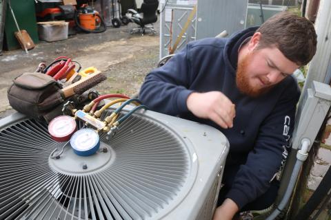 Sunshot by Grayson Williams - McGee Heating and Air technician Kyle Risner, a Hartwell native,  makes repairs to an air conditioning unit recently in Hartwell.