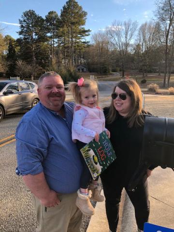 Charlie and Kim Pierce pose for a picture with their daughter, Camille, and a book provided by the Imagination Library.  Photo submitted