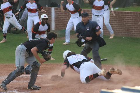 Will Dean slides head-first into home plate and beats the tag to add another run in the Diamond Dogs’ late-inning surge to take a 3-1 victory over region rival Franklin County as fellow Bulldogs celebrate in front of him at home on Tuesday, March 30.